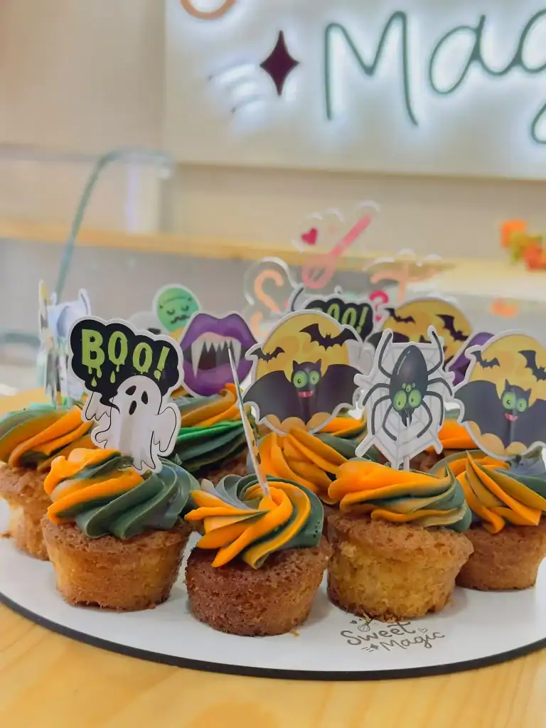 Cupcakes de Halloween con buttercream naranja y verde y toppers de fantasma, murciélago, araña y vampiro en el obrador de Sweet Magic en Madrid